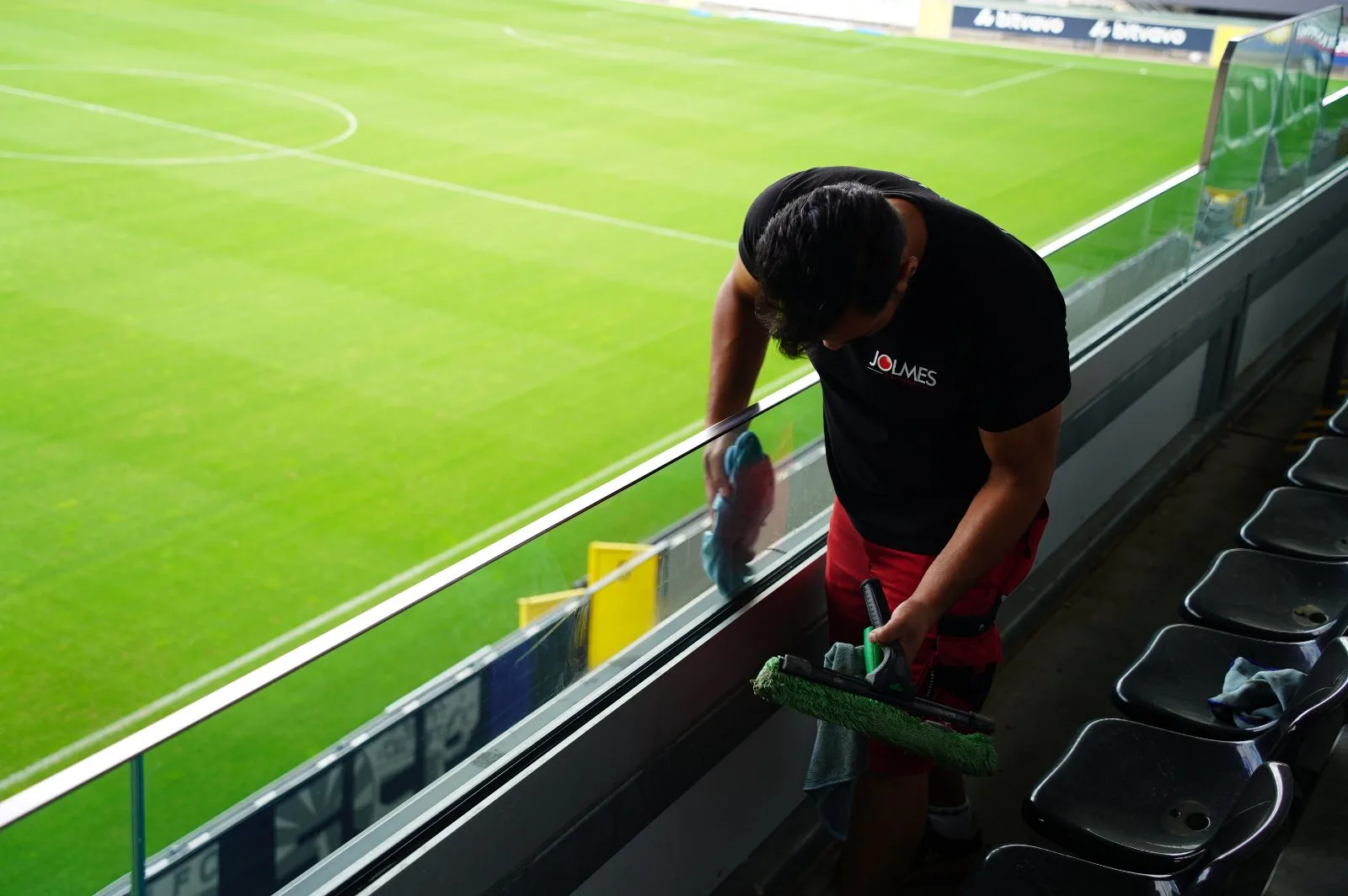 Jolmes Mitarbeiter reinigt die Glasfront einer Stadiontribüne